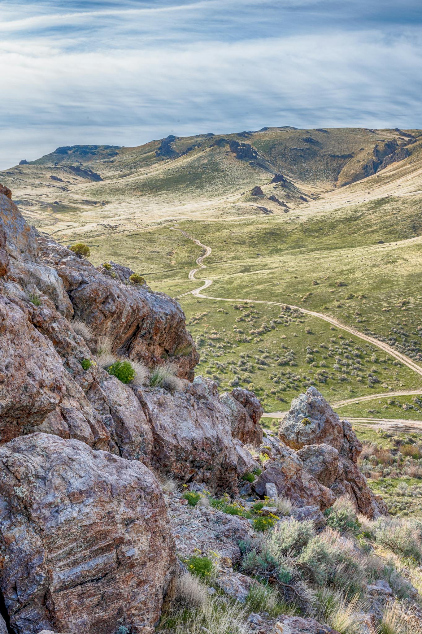 High angle from rocky mountain top breathtaking landscape of spacious green highlands against majestic cloudy sky